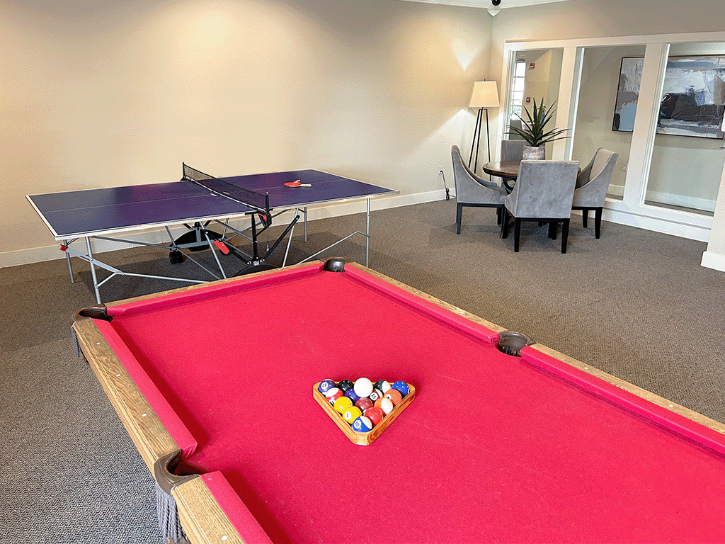 A pool table with a red cloth and a set of pool balls.